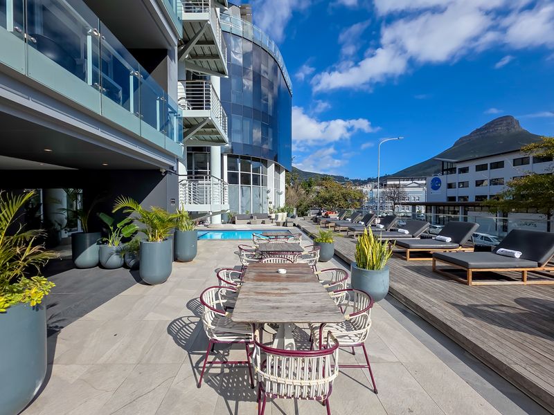 Spacious outdoor pool area featuring a swimming pool, timber decking, and tiled patio with glass balustrades, offering a modern penthouse lifestyle setting.