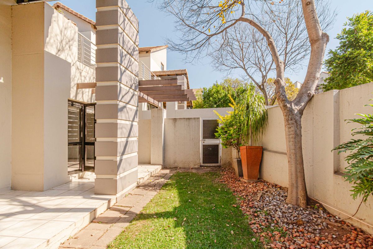 Rear courtyard area featuring a tiled patio, pergola structure, and a small garden space with boundary walling.