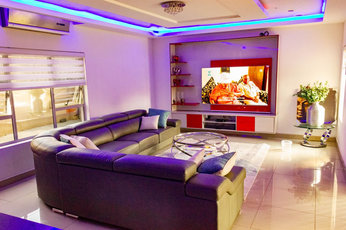 Modern living room featuring a built-in media wall, recessed LED ceiling lighting, split-system air conditioning, and polished tiled flooring.