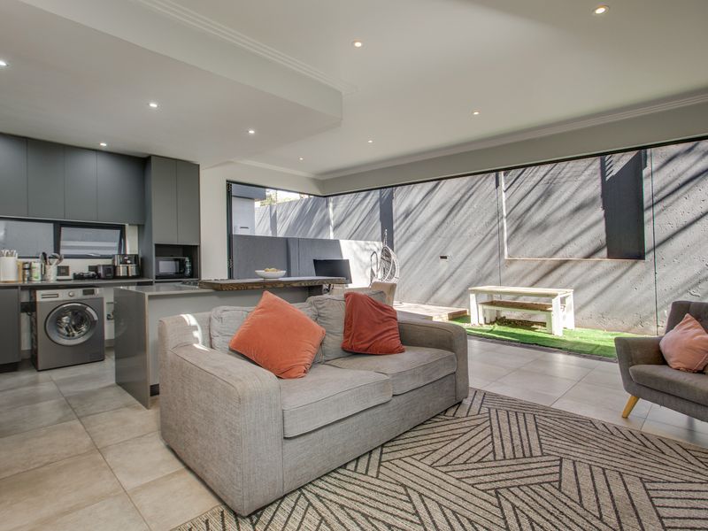Modern open-plan living area featuring a sleek kitchen with built-in cabinetry, tiled floors, and large sliding doors opening to a private outdoor space.