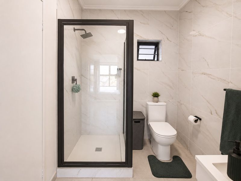 Modern bathroom featuring a walk-in shower with a black-framed glass enclosure, rain shower head, and contemporary marble-look wall tiling.