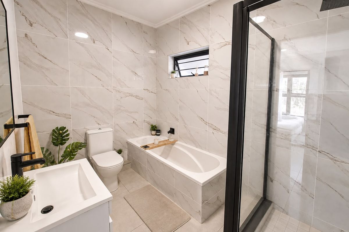 Modern bathroom featuring a walk-in shower with black frame, built-in bathtub, vanity basin, and elegant marble-look wall tiles.