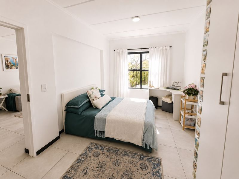 A bright and well-maintained bedroom featuring neutral tiled flooring, a built-in desk area, and a built-in cupboard, offering a clean and functional living space.