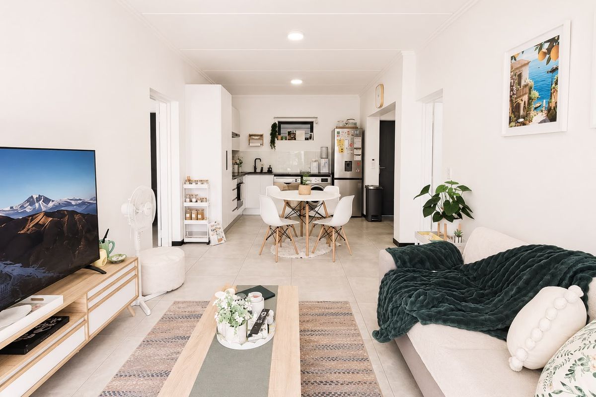 A bright open-plan living and dining area featuring tiled floors, recessed lighting, and a functional kitchen layout with modern cabinetry.