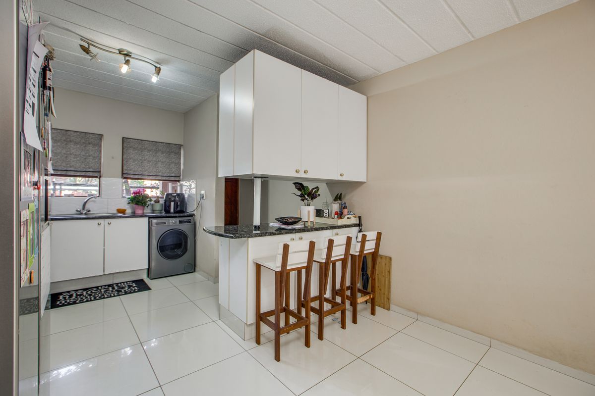 A functional kitchen featuring white cabinetry, granite countertops, a breakfast bar, and tiled flooring, providing a practical layout for daily use.