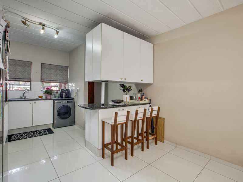 A functional kitchen featuring white cabinetry, granite countertops, a breakfast bar, and tiled flooring, providing a practical layout for daily use.