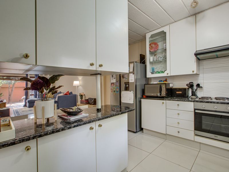 Functional kitchen featuring white cabinetry, granite countertops, built-in oven, and hob, with an open-plan layout connecting to the living area.