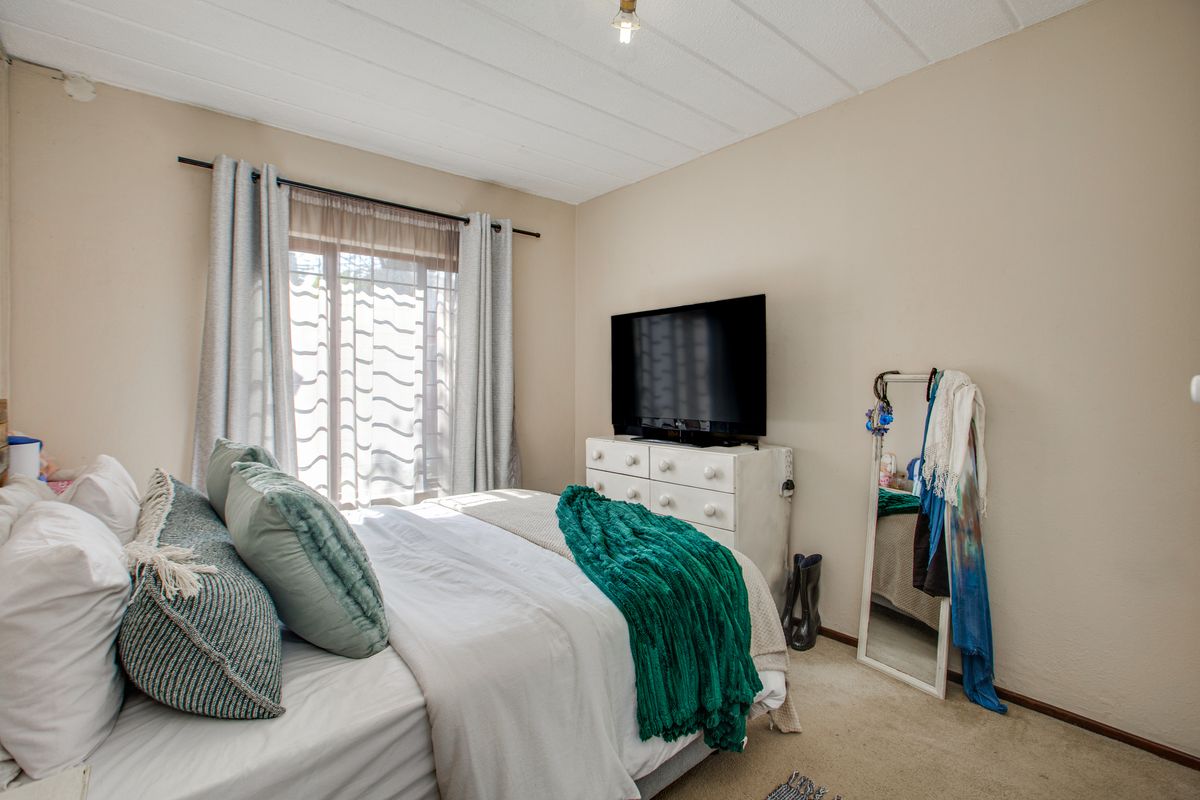A standard bedroom featuring carpeted flooring, a textured ceiling, and a sliding glass door providing natural light.