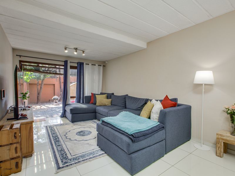 A bright living room featuring tiled flooring, track lighting, and a sliding glass door providing direct access to the outdoor patio area.