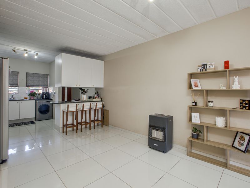 Open-plan living area featuring tiled flooring, a modern kitchen with built-in cabinetry, granite countertops, and a breakfast bar for casual dining.