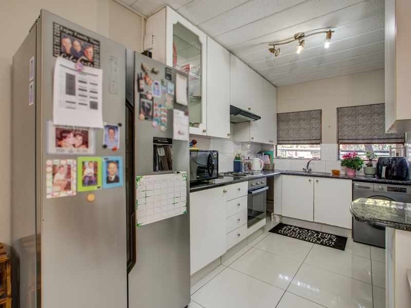A functional kitchen featuring white cabinetry, granite countertops, built-in oven, extractor fan, and tiled flooring.