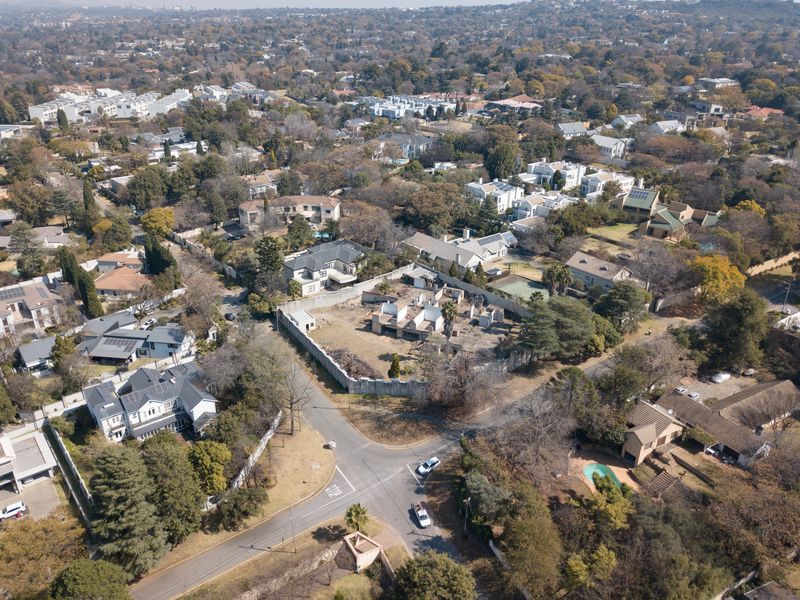 Aerial view of a residential vacant land plot featuring an incomplete building structure and perimeter walling in an established suburban neighborhood.
