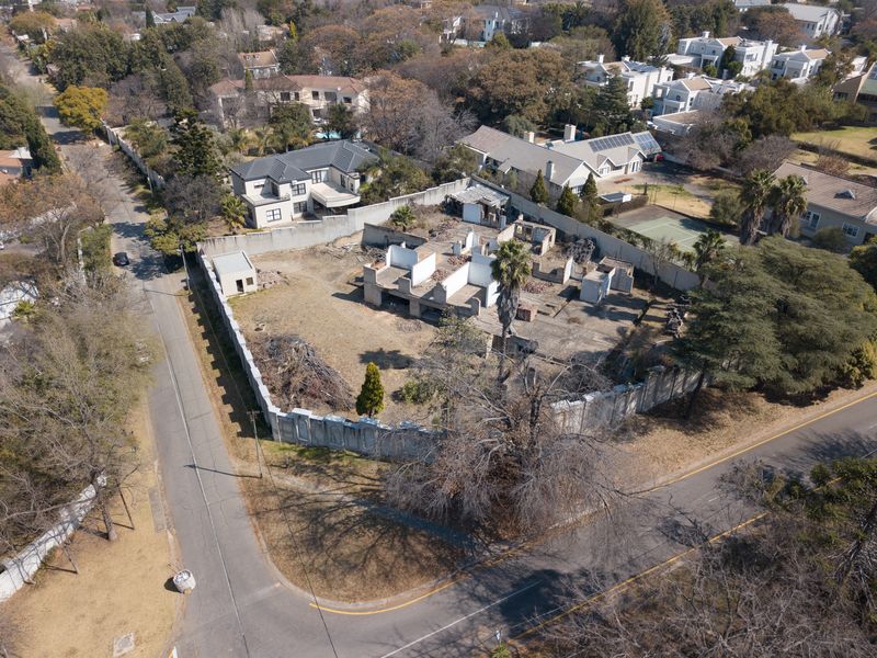 Aerial view of a vacant residential plot featuring a concrete slab foundation and perimeter walling, situated on a corner stand in a suburban area.