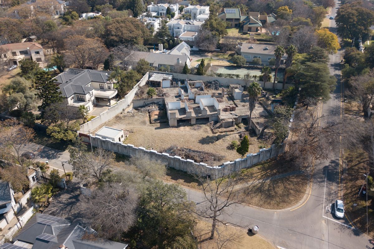 Aerial view of a residential vacant land plot featuring a partially constructed building shell and perimeter walling in an established neighborhood.