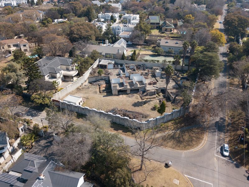 Aerial view of a residential vacant land plot featuring a partially constructed building shell and perimeter walling in an established neighborhood.