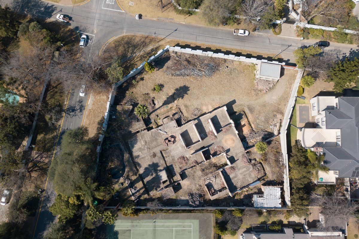Aerial view of a vacant residential plot featuring an incomplete concrete foundation and perimeter walling in a suburban neighborhood.