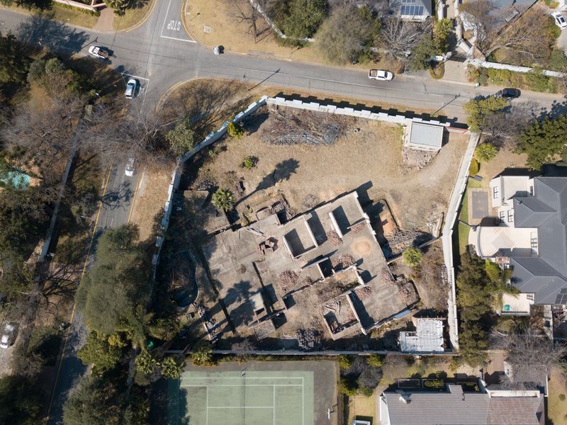 Aerial view of a vacant residential plot featuring an incomplete concrete foundation and perimeter walling in a suburban neighborhood.