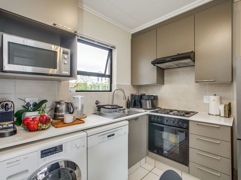 A compact, well-maintained kitchen featuring modern cabinetry, stone countertops, integrated appliances, and a tiled backsplash, offering efficient workspace and storage.