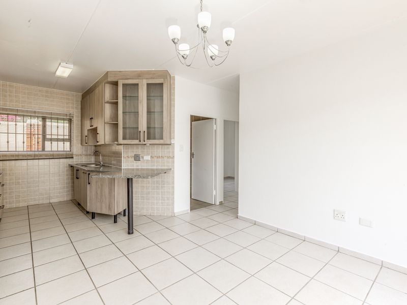 Open plan kitchen and living area featuring light wood cabinetry, granite countertops, tiled flooring, and a neutral color palette throughout.