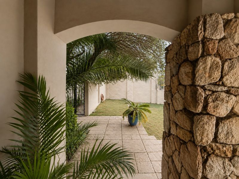 A covered patio area featuring an arched entryway and stone cladding, leading out to a private garden space.