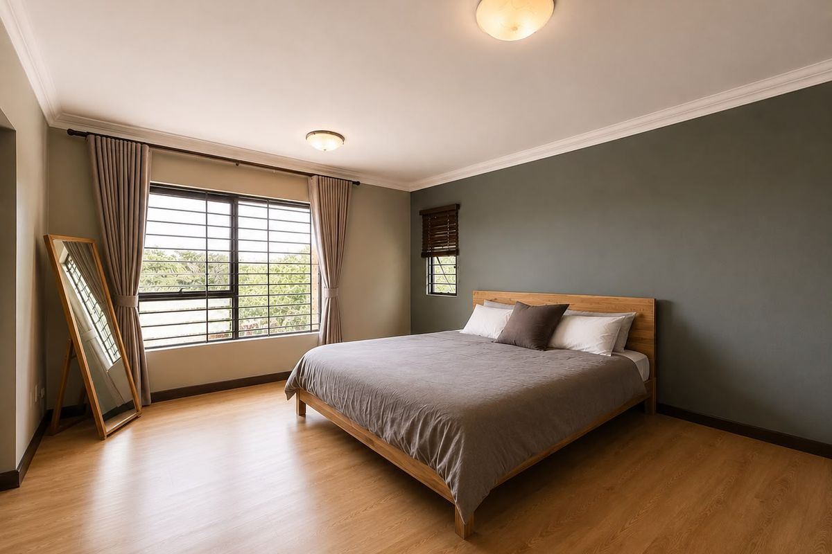 A well-maintained bedroom featuring laminate flooring, crown molding, and large windows with security bars, offering a clean and neutral living space.