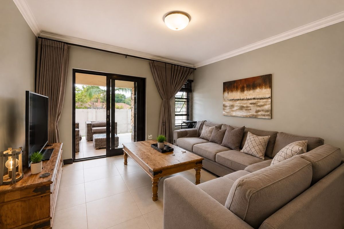 A well-maintained living room featuring tiled flooring, neutral walls, and large sliding glass doors providing direct access to an outdoor patio area.