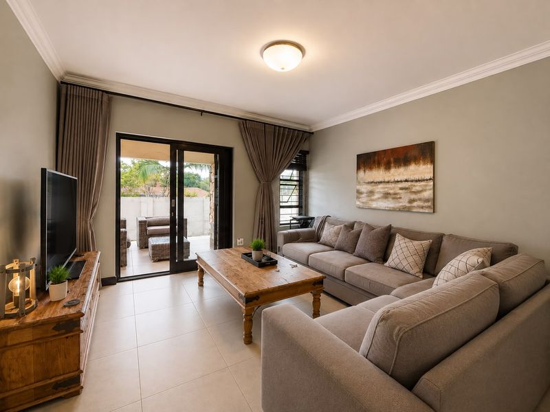 A well-maintained living room featuring tiled flooring, neutral walls, and large sliding glass doors providing direct access to an outdoor patio area.