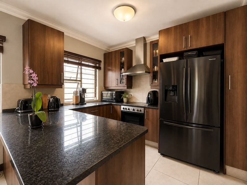 A well-maintained kitchen featuring dark wood cabinetry, granite countertops, stainless steel extractor fan, and built-in oven with neutral tile flooring.