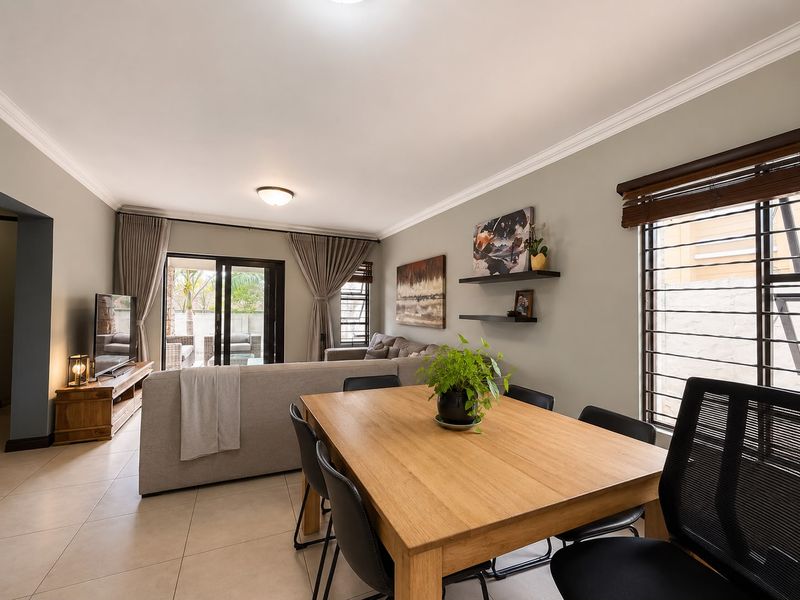 An open-plan living and dining area featuring neutral tiled floors, crown molding, and large sliding glass doors providing access to the outdoor patio.