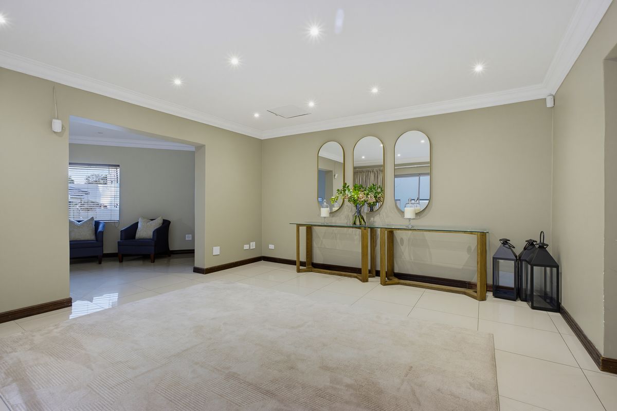 Spacious living area featuring neutral wall tones, recessed downlighting, coved ceilings, and polished tiled flooring throughout.