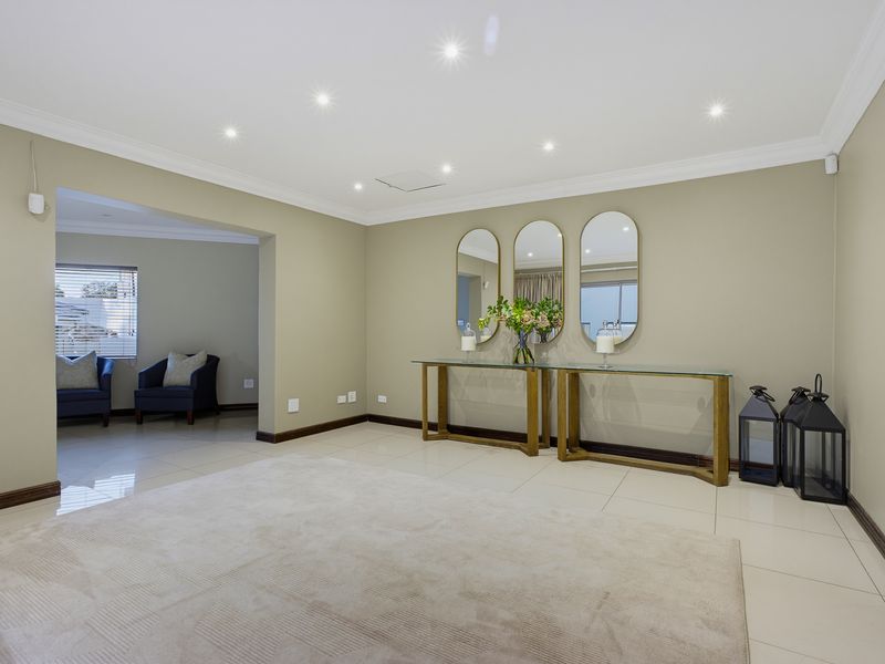 Spacious living area featuring neutral wall tones, recessed downlighting, coved ceilings, and polished tiled flooring throughout.