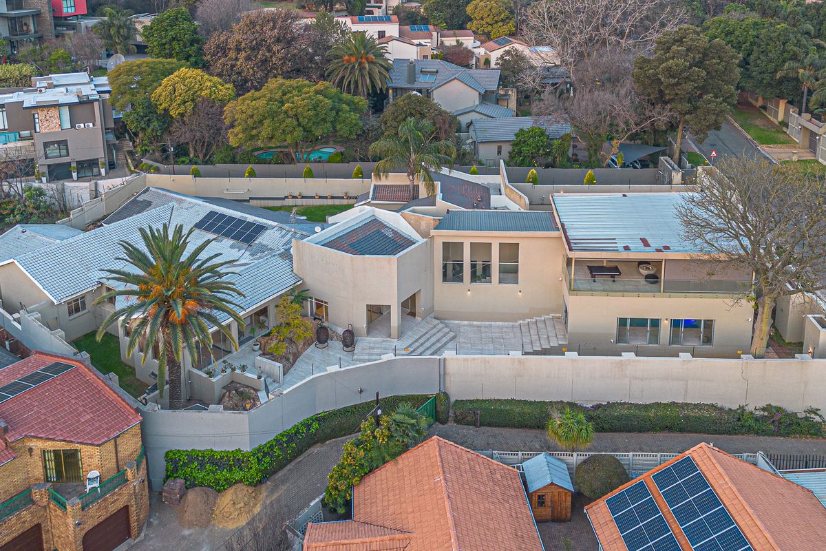 Aerial view of the property showcasing the building layout, roof structure, solar panels, and paved outdoor courtyard area.