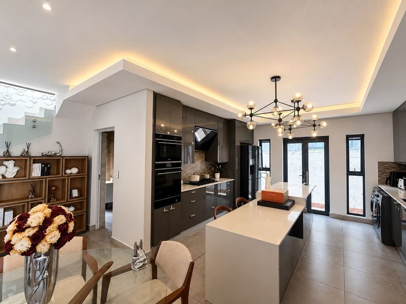 Modern open-plan kitchen featuring high-gloss cabinetry, a central island, integrated appliances, and elegant recessed lighting, seamlessly flowing into the dining area.