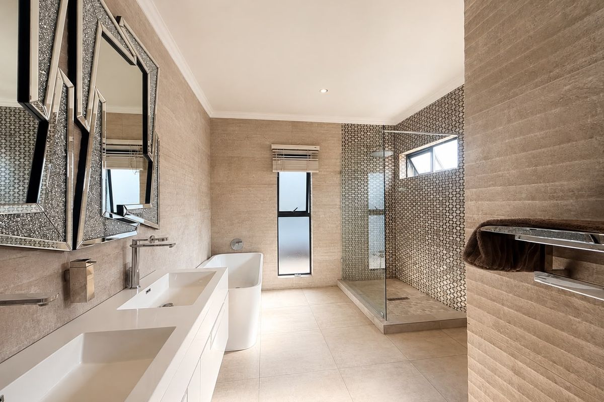 Modern bathroom featuring a double vanity, freestanding bathtub, and a spacious walk-in shower with mosaic tile accents and high-quality finishes.