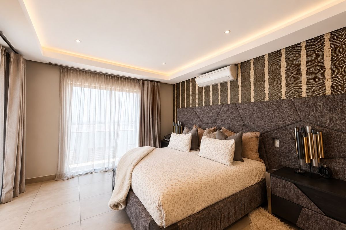 Modern bedroom featuring tiled flooring, recessed cove lighting, a split-system air conditioner, and a large sliding glass door leading to a balcony.