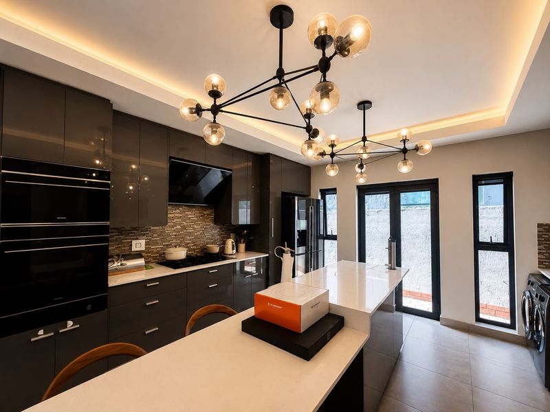 Modern kitchen featuring high-gloss cabinetry, a central island with quartz countertops, built-in appliances, and stylish pendant lighting, offering a sleek and functional workspace.