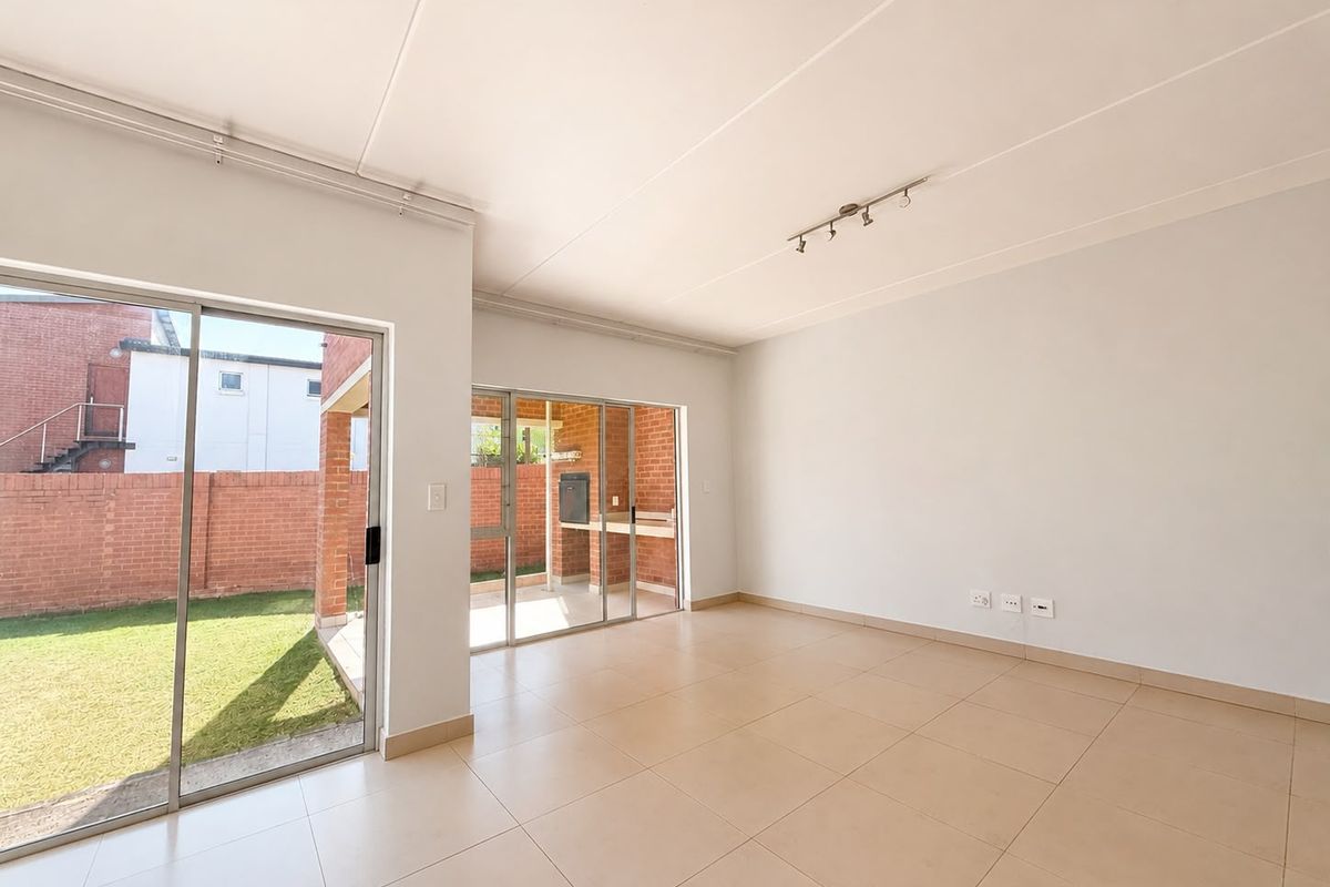 Spacious, light-filled living area featuring neutral tiled flooring and large sliding glass doors providing seamless access to the outdoor patio and garden.