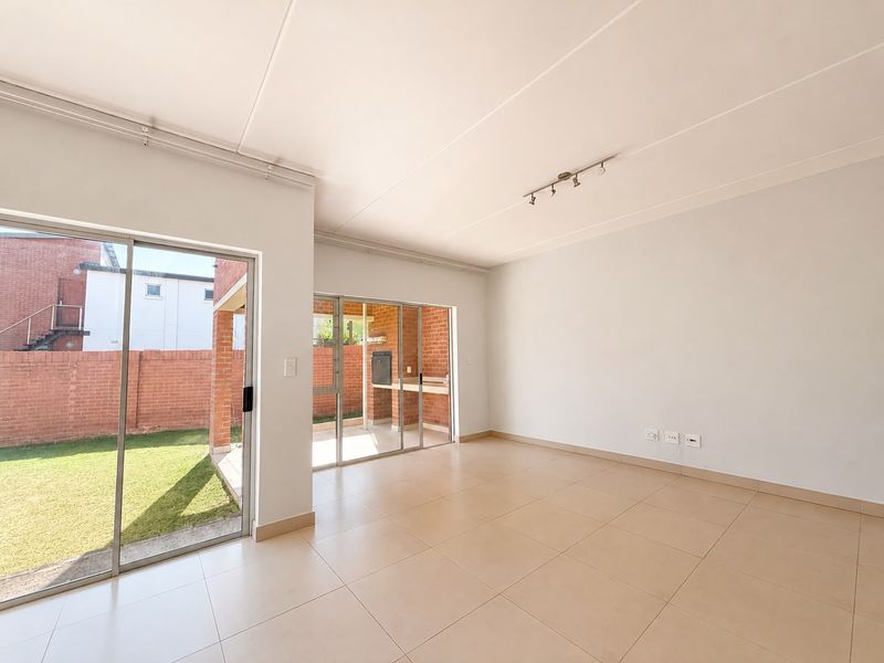 Spacious, light-filled living area featuring neutral tiled flooring and large sliding glass doors providing seamless access to the outdoor patio and garden.