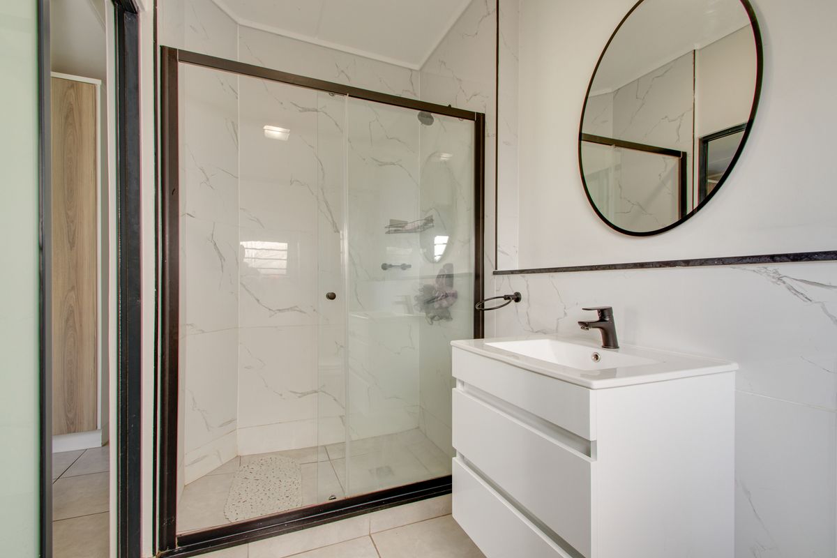 Modern bathroom featuring a glass shower enclosure, sleek vanity cabinet with basin, and contemporary marble-look wall tiling.