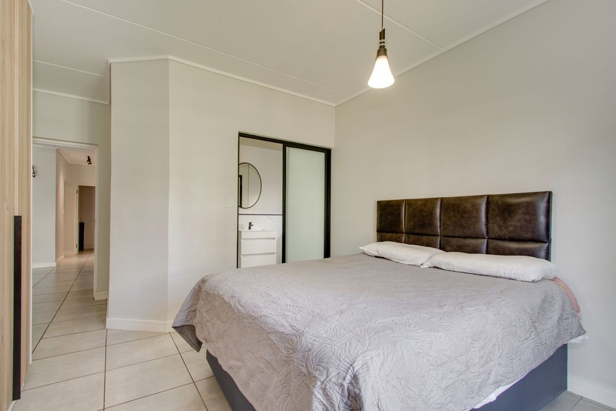 A well-maintained bedroom featuring tiled flooring, a built-in wardrobe, and direct access to an en-suite bathroom.