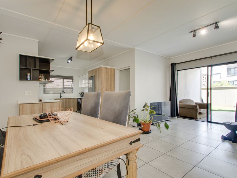 Open-plan living and dining area featuring modern kitchen cabinetry, tiled floors, and large sliding doors leading to an outdoor patio space.