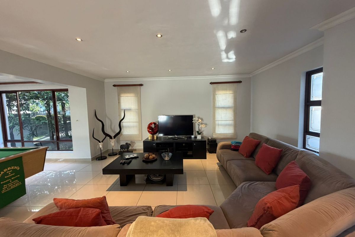 Spacious living room featuring polished tiled flooring, recessed downlighting, and large windows providing natural light and access to the outdoor area.