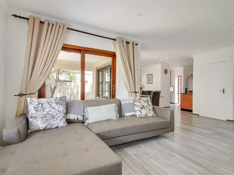 Spacious open-plan living area featuring modern laminate flooring, recessed lighting, crown molding, and a large timber sliding door leading to the outdoor space.