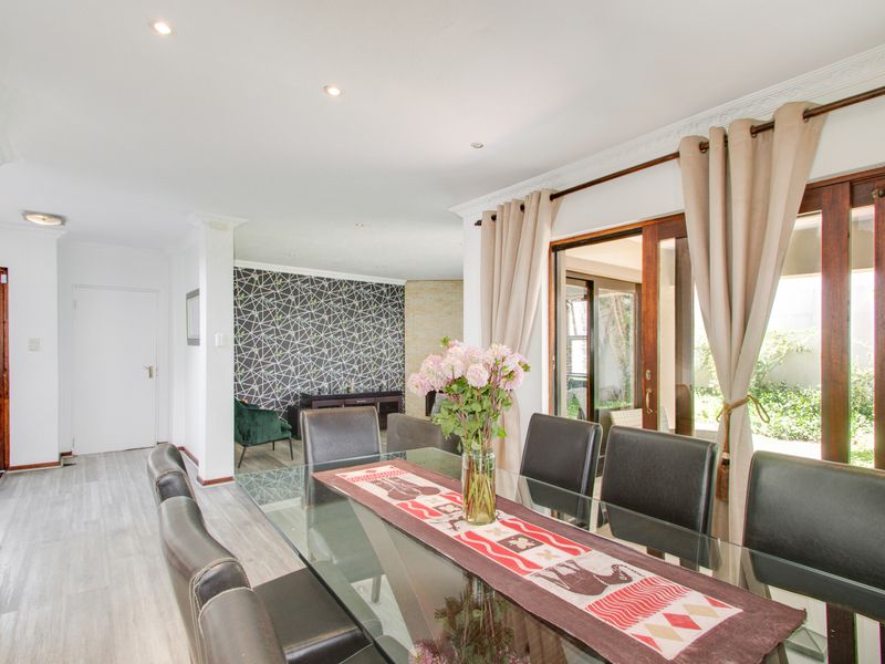 Bright dining area featuring laminate flooring, decorative cornice, and wooden sliding doors providing direct access to the outdoor patio area.