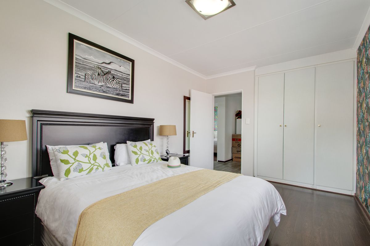 A well-maintained bedroom featuring laminate flooring, built-in cupboards, and neutral wall finishes, offering a clean and functional living space.