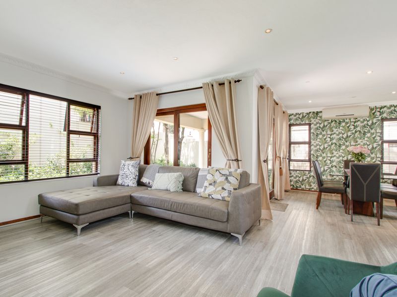 Bright open-plan living and dining area featuring modern laminate flooring, recessed lighting, and sliding glass doors leading to the outdoor space.