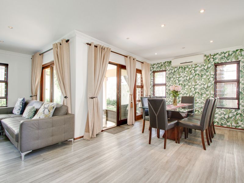 Bright open-plan living and dining area featuring modern laminate flooring, recessed lighting, and direct access to the outdoor patio through sliding glass doors.