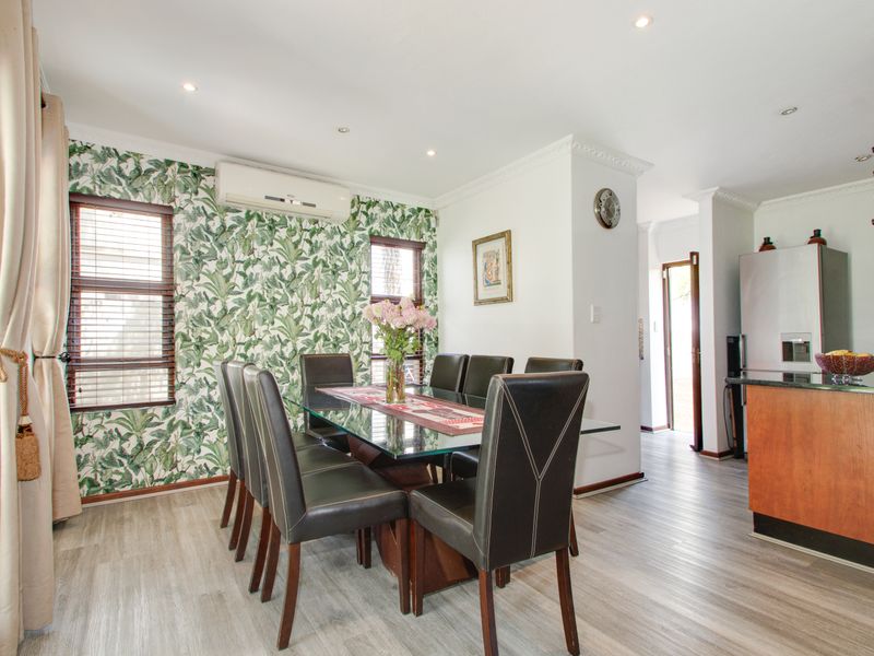 Open-plan dining area featuring laminate flooring, crown molding, recessed lighting, and a split-system air conditioner, seamlessly connected to the kitchen space.