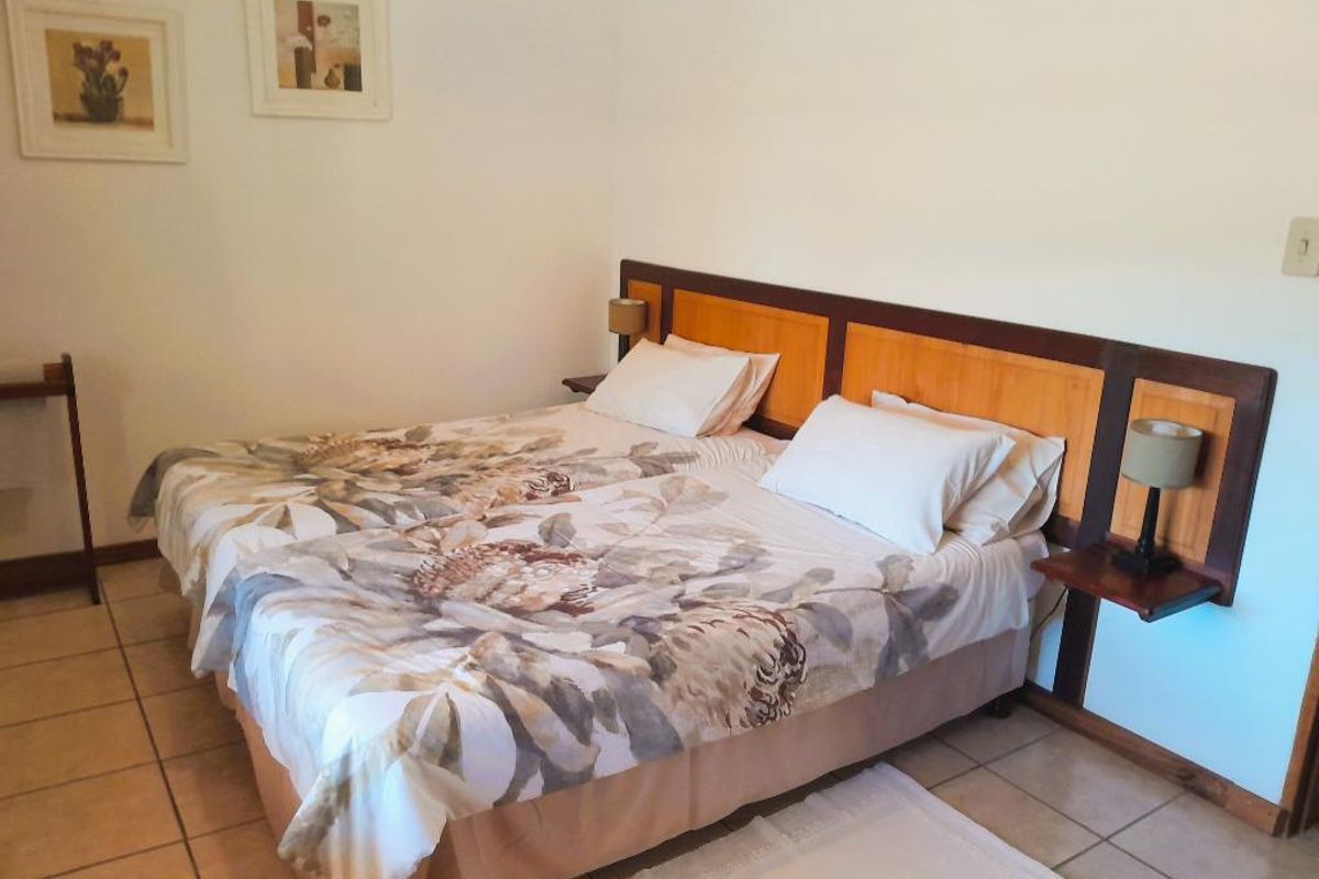 A bedroom featuring a built-in wooden headboard with integrated bedside shelves and tiled flooring.