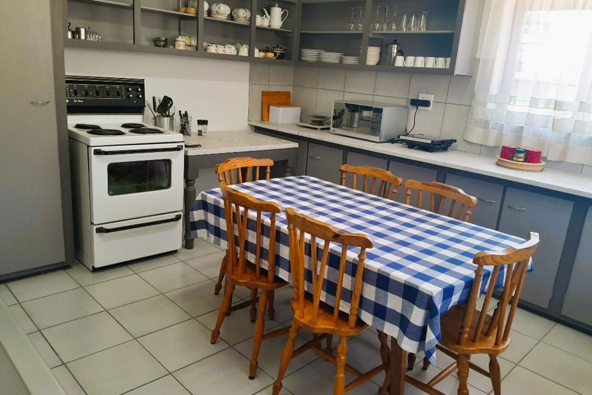 A functional kitchen featuring grey cabinetry, tiled flooring, a freestanding stove, and ample counter space, providing a practical layout for daily meal preparation.